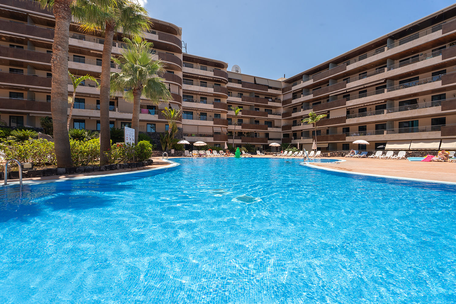 View of water and palm trees by the pool at Teide View Balcones de Los Gigantes.
