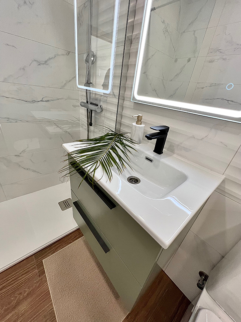 Sink area in the apartment bathroom, elegant furniture with a large mirror and natural light.