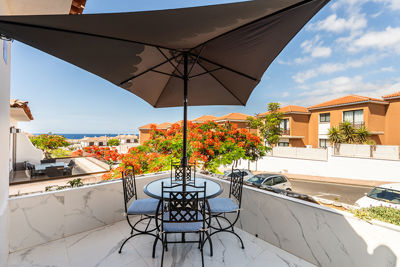 Terrace with umbrella and outdoor dining area surrounded by colorful vegetation.