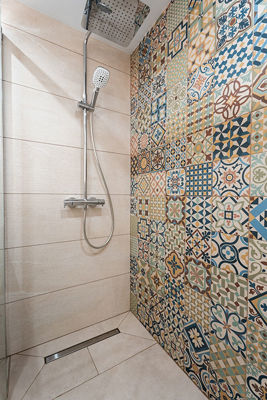 Shower cabin with designer fixtures and decorative tiles in the apartment bathroom.