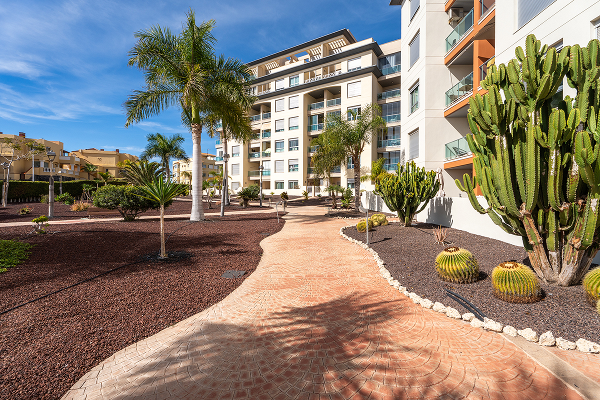 Spacious garden in a serene setting with tropical plants and outdoor furniture at the vacation apartment in Golf del Sur, Tenerife
