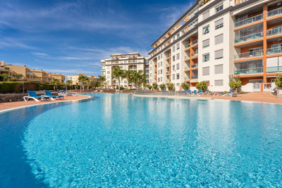 Large pool surrounded by loungers and palm trees in the vacation apartment in Canary Islands, Spain