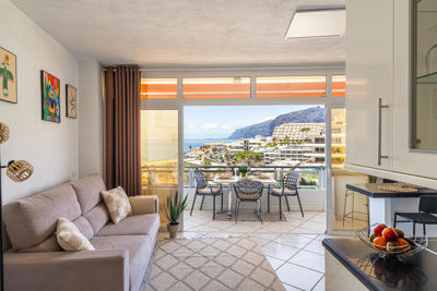 Spacious living room with large windows and modern decor in a vacation rental in the Canary Islands.